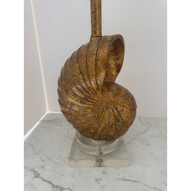 Unique seashell form table lamp in gilt finish resting on a lucite base. The base is constructed of a circular lucite base...