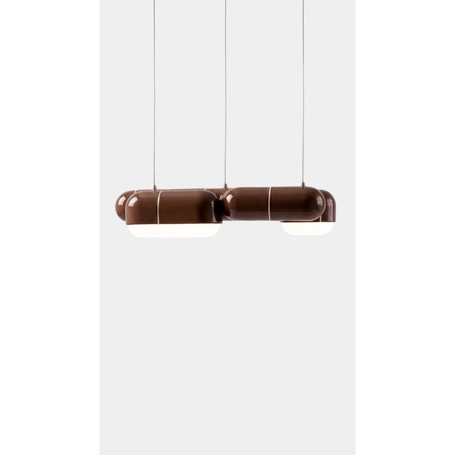 A linear pendant made for the table everyone gathers around. The curved-tile module repeats along its length, so light...
