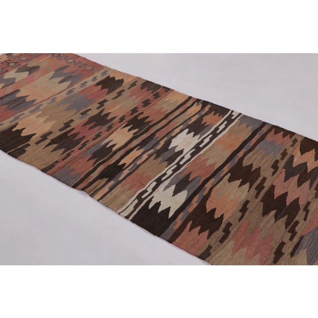 Made with handwoven wool circa 1950-1960, this 3x9 vintage flat-weave runner Kilim is a particularly nuanced and sought-...