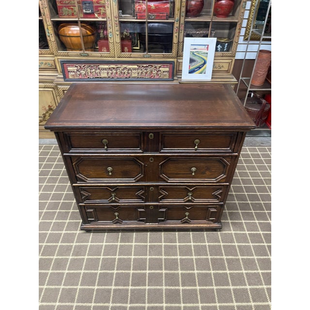 An English Georgian period oak chest of drawers with a rectangular planked top with molded edges, beautifully carved...