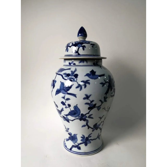 his blue and white porcelain jar is adorned with hand painted lovely birds on the tree branches. Antiquing process applied...