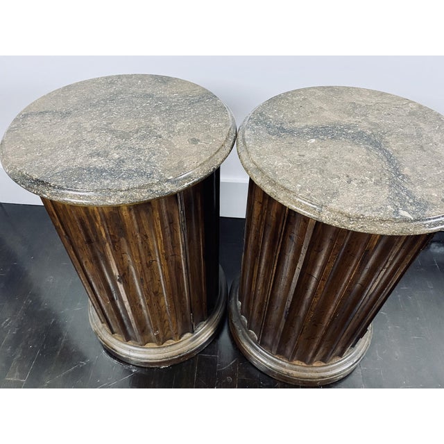 A pair of neoclassical style wooden column pedestal-shaped side tables with handsome marble tops with molded edge, fluted...