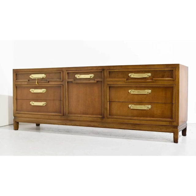 Commanding in scale and refined in detail, this mid-century Campaign style credenza by Fancher Furniture is a rare find...