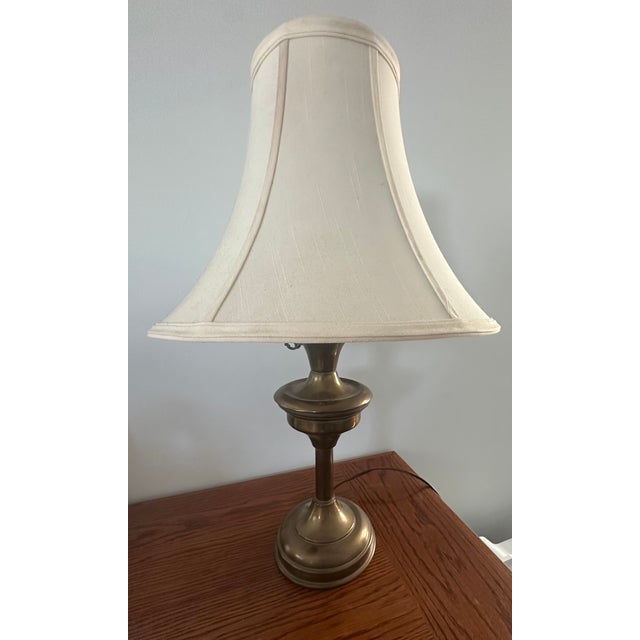 Warm vintage brass meets whimsical detail: this elegant table lamp features a gently flared bell shade that casts a soft,...