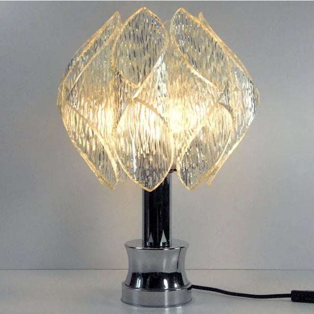 A decorative lamp designed in Space Age style. The lamp base is made of chrome metal. The shade is made of transparent...