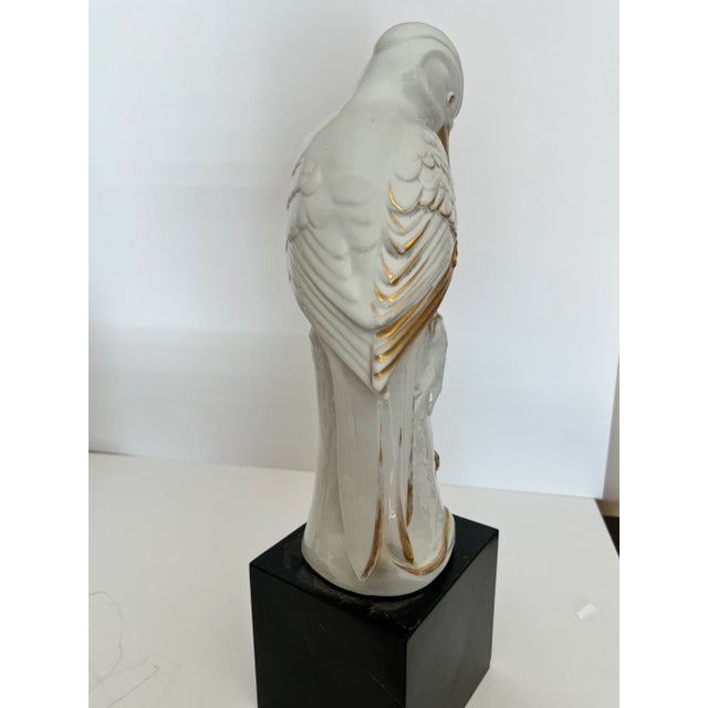 Beautiful white Heron sitting on a tree branch with bug and leaves on a black marble base. It has gold painted bill and...