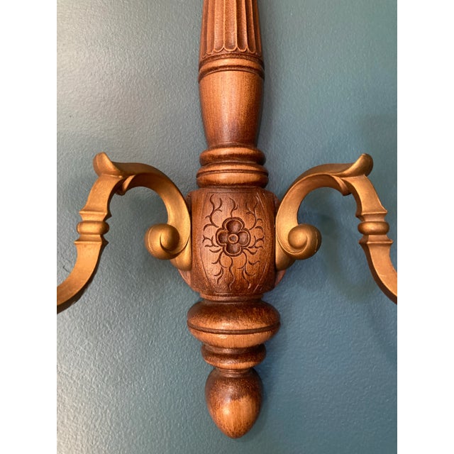 Nice mid-century wood and resin candle sconce. It features a carved floral pattern on the bottom. Sconce arms are gold...