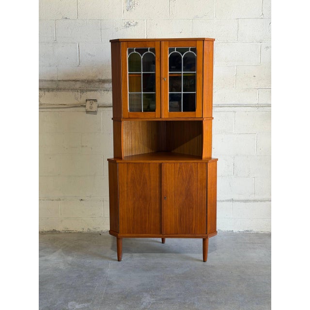 Beautiful vintage Danish modern teak corner cabinet made in Denmark, featuring an elegant space-saving design with...