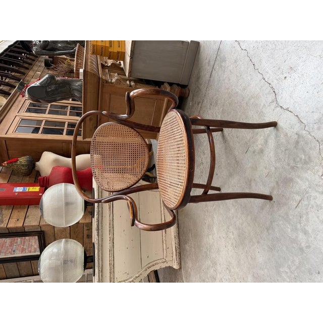 This vintage armchair features a bentwood frame and base (beech) and a seat and backrest made of cane (in perfect...
