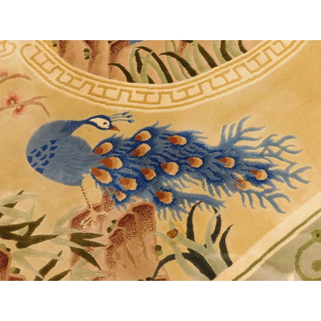 Golden central medallion depicting a peacock displaying its feathers. Corners decorated with additional peacocks. Border...