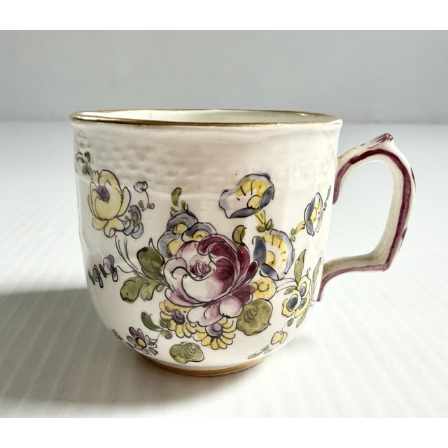 Antique small porcelain cup with handpainted flowers and a crest and crown.
