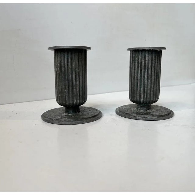 A pair of patinated candleholder in patinated pewter. Fluted design reminiscent of Corinthian Columns. In the style of...