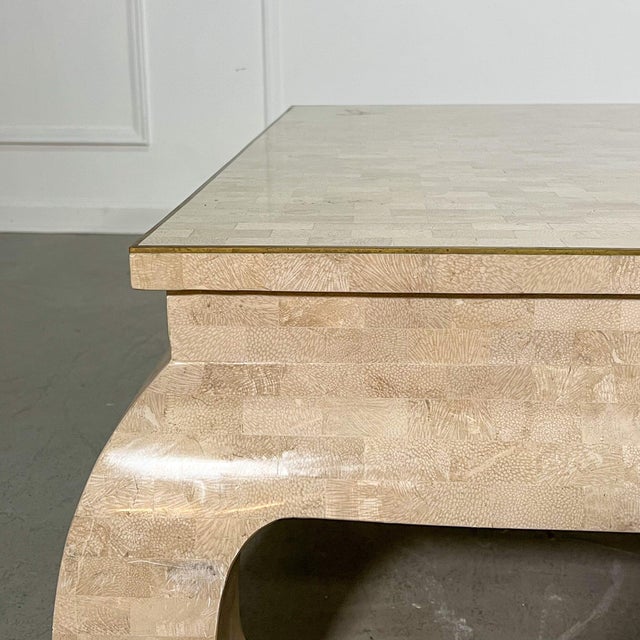 A monumental tessellated stone coffee table with shapely Ming style legs and brass inlay that borders a tapered edge....