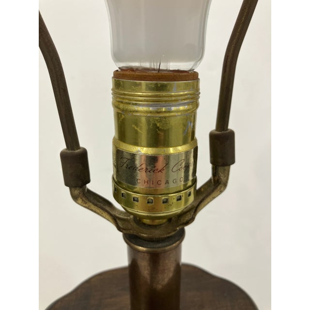 This signed Frederick Cooper lamp is solid brass with a bronze patina. The cap and base are solid wood. The form is styled...