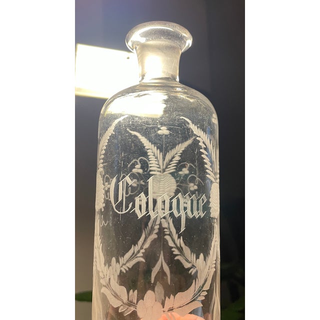 Antique engraved glass cologne bottle, engraved with flora swags all the way around and the word Cologne centered on the...
