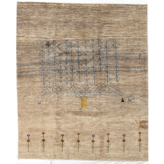 Hand-knotted Persian Lori Gabbeh rug featuring a soft natural field with a large stylized tree of life rendered in...