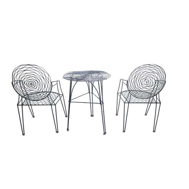 Charming and unique wrought iron patio set includes two chairs and one table. Chair backings and tabletop feature a...