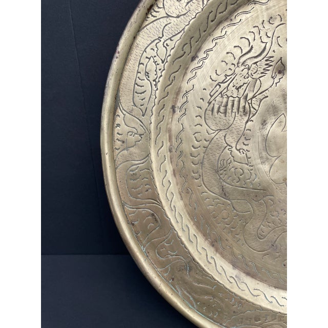 1930s Chinese brass charger or tray with two dragons in the well surrounding a Chinese character. The rim has more dragons...