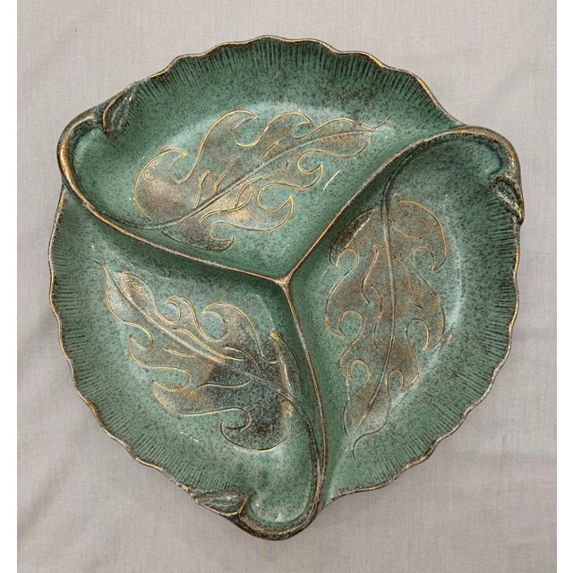A vibrant mottled mint green color highlighted by gold accents highlights three (3) intricate leaf-shaped sections. A...