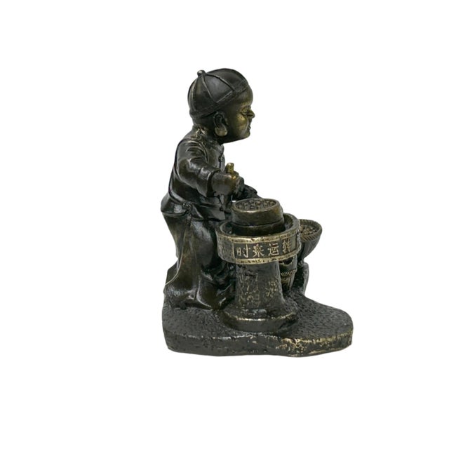 Presenting a charming bronze figurine depicting a child engaged in the traditional process of grinding, likely soybeans,...