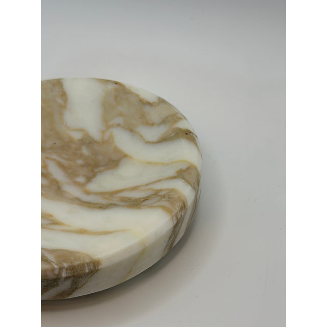 Elegant round marble soap dish by Waterworks, featuring dramatic natural cream and warm beige veining. Sculpted with a...