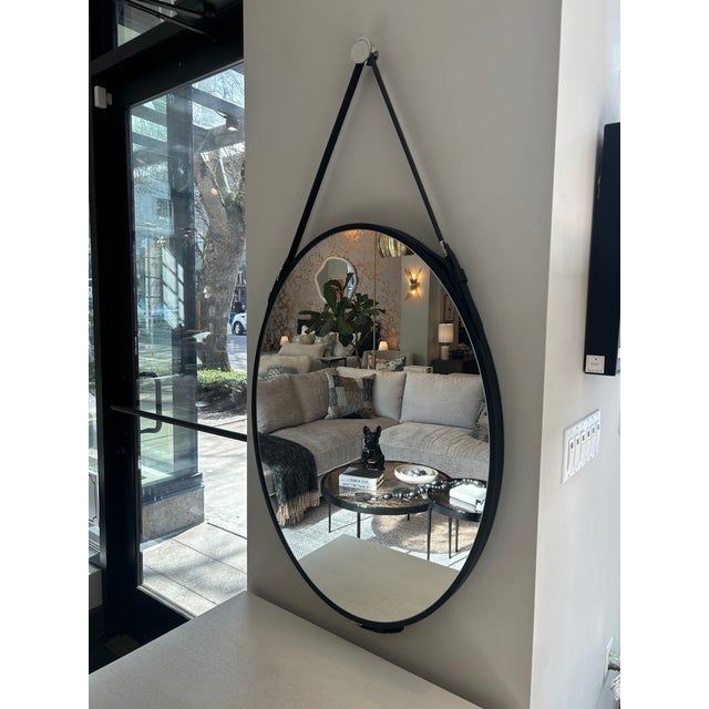 Oval mirror with black faux leather straps and metal belt buckles. Curated by Arden Home. Reg $650, Now $500