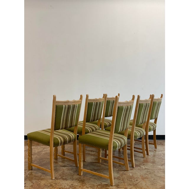 Oak dining chairs with green striped wool upholstery, in the style of Henning Kjaernulf. Brass tack accents.