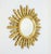Decorative sunburst wall mirror crafted in carved giltwood (gold-painted/leaf-effect wood), featuring a circular central...