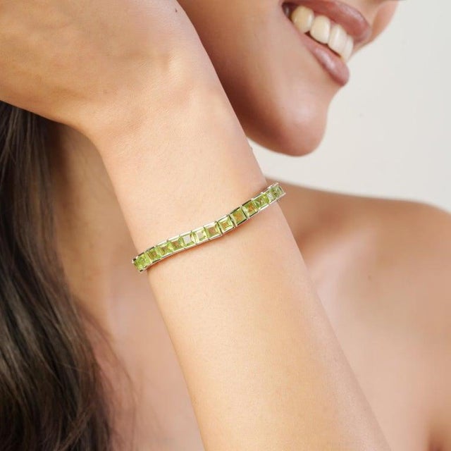 Stunning square cut peridot tennis bracelet crafted in solid sterling silver, featuring an impressive 14.62 carats total...