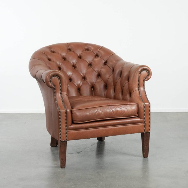 We are offering this cognac-colored Chesterfield club armchair made of cowhide leather in English style, finished with...