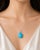 This elegant pendant necklace is crafted in 14K white gold and features a striking oval turquoise accented with shimmering...