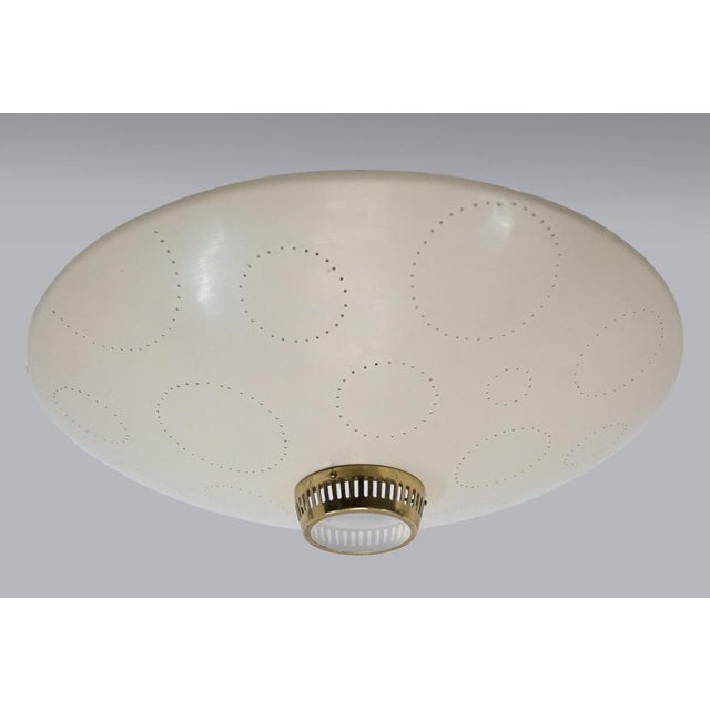 Elegant flush mount ceiling light comes with a disc shaped enameled metal reflector with circular perforations of...