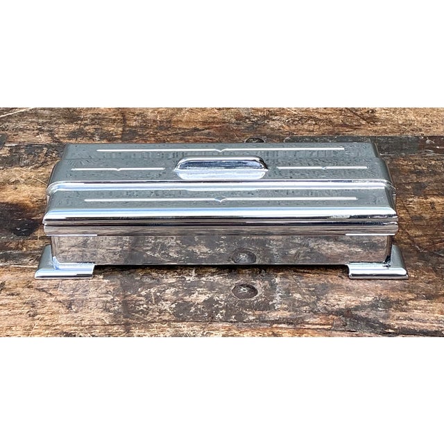 Vintage Art Deco Metal Lidded Box with a streamlined rectangular silhouette, stepped edges, and four bracket feet that...