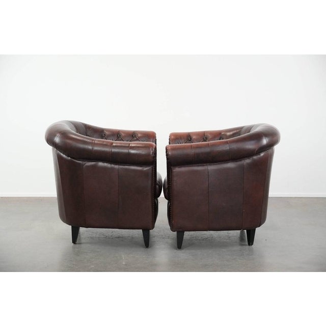 Offered is this set of two classic English-style Chesterfield club chairs in cowhide leather, finished with decorative...