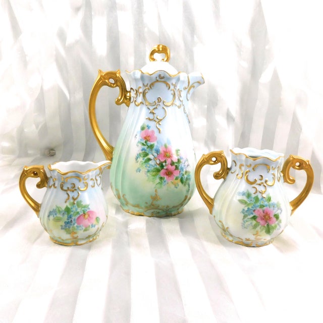 This is a pale blue hand painted and hand decorated teapot, sugar bowl (with no lid), and creamer. The set is signed To...
