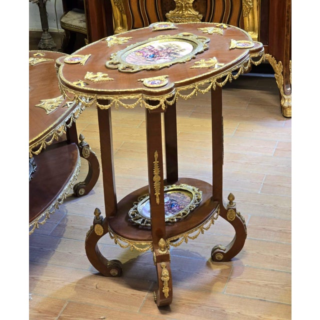 A beautifully ornate French Rococo Revival side table featuring an elegant two-tier design, warm wood tones, and exquisite...