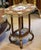 A beautifully ornate French Rococo Revival side table featuring an elegant two-tier design, warm wood tones, and exquisite...