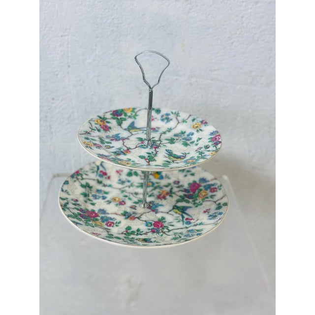 This is a two-tier porcelain serving stand featuring decorative plates with a colorful floral and bird motif. The plates...