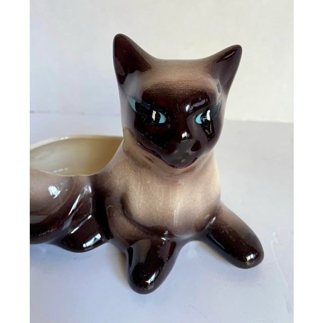 Here is a lovely, porcelain Siamese Cat figurine that has an open back for holding trinkets, a plant, etc. It looks...