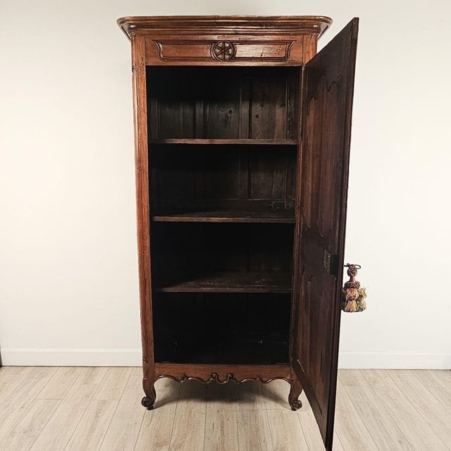A French fruitwood bonnetière (hat cabinet), early 19th century, on scrolling feet with beautiful paneled door. Great...