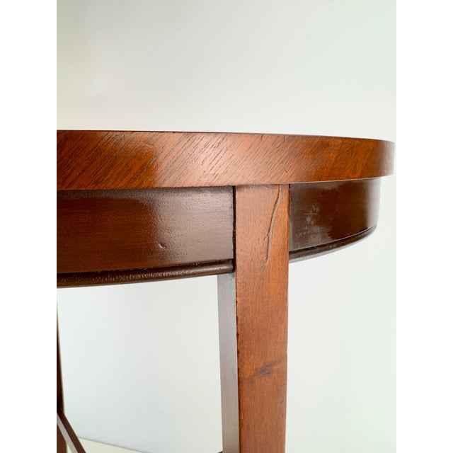 An elegant vintage oval side table featuring a rich reddish-brown mahogany finish and a beautifully understated...