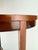 An elegant vintage oval side table featuring a rich reddish-brown mahogany finish and a beautifully understated...