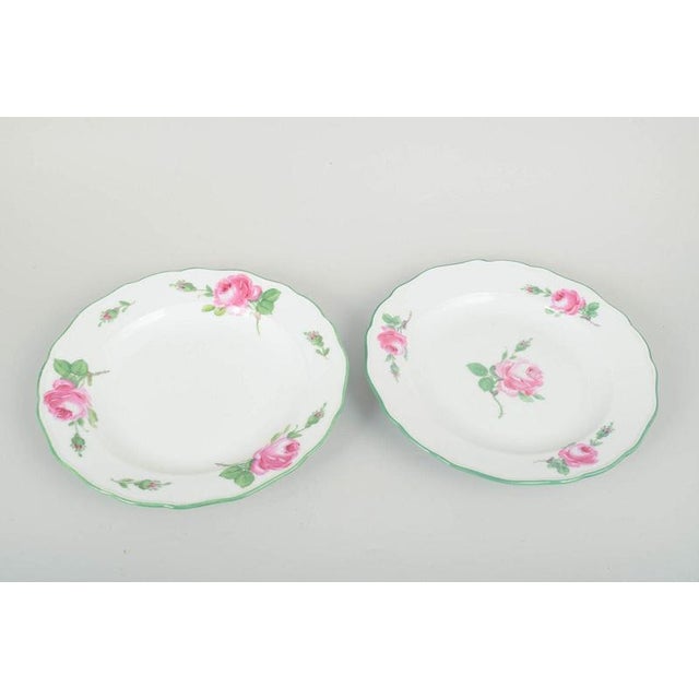 Meissen two dinner plates, 1930s. Beautiful porcelain plates with hand-painted pink roses and a green rim along the...