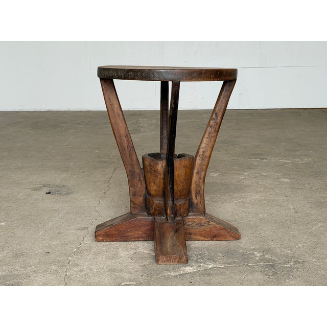 Striking primitive sculptural side table handcrafted from solid wood, likely mid-20th century. The piece features a richly...