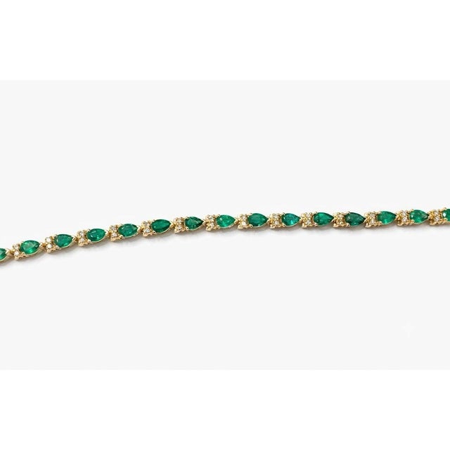 A striking 14K gold tennis bracelet featuring natural pear-shaped emeralds accented by sparkling round brilliant-cut...