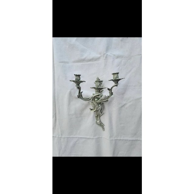 Pair of heavy wrought iron sconces that can hold three candles each. The color is a soft antiqued green. These sconces are...