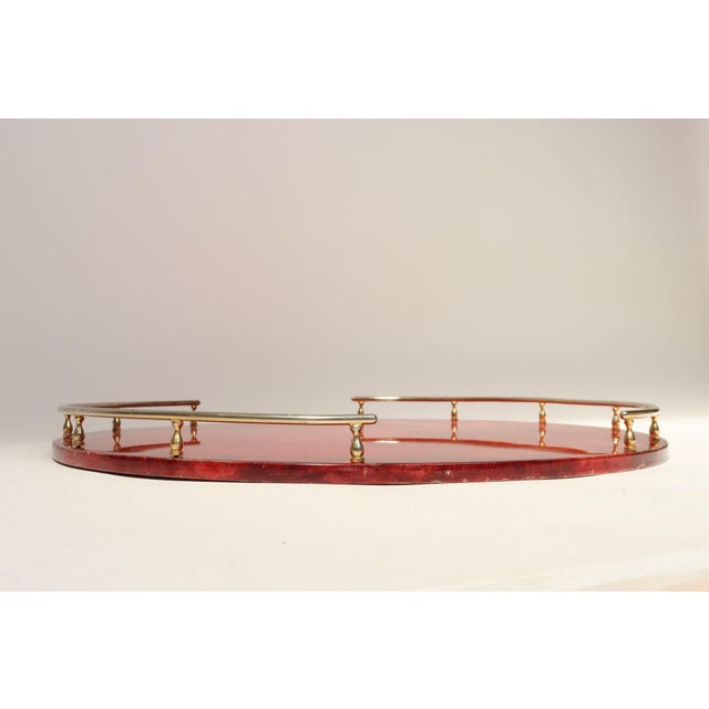 Large Aldo Tura circular walnut tray wrapped in lacquered dyed-red goatskin with dual brass semicircular trim (ca. 1950s,...