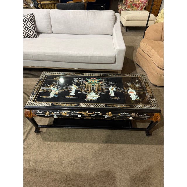 Elegant vintage chinoiserie coffee table featuring a glossy black lacquered finish with intricate shellwork detailing and...