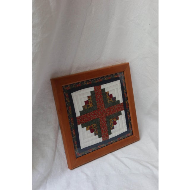 Log Cabin quilt square, featuring a traditional red center block surrounded by white and patterned green fabric strips...