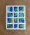 A vibrant geometric watercolor featuring twelve interconnected panels in rich cobalt blue, sea-glass green, and earthy...